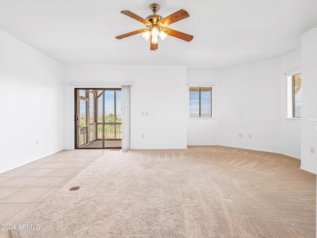 spare room with a ceiling fan, light tile patterned flooring, and light colored carpet