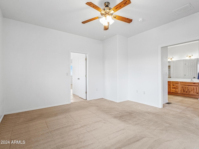 unfurnished bedroom featuring visible vents, light carpet, a sink, connected bathroom, and baseboards