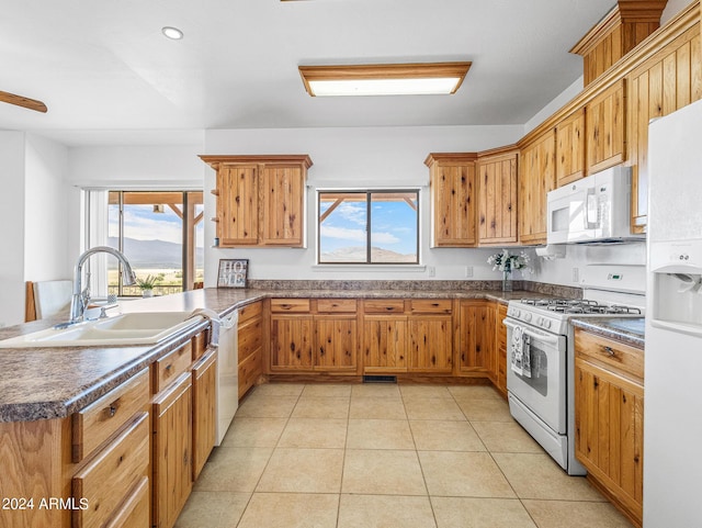 kitchen with white appliances, light tile patterned flooring, dark countertops, and a sink