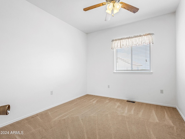 carpeted spare room featuring visible vents, baseboards, and a ceiling fan