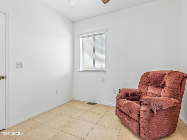 living area with light tile patterned floors, visible vents, baseboards, and ceiling fan