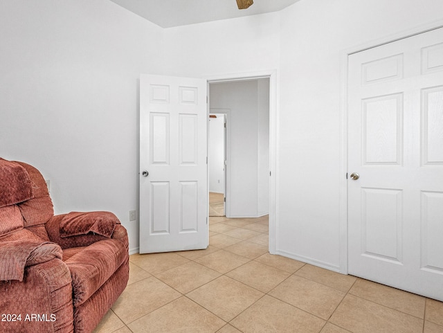 sitting room with ceiling fan, baseboards, and light tile patterned flooring