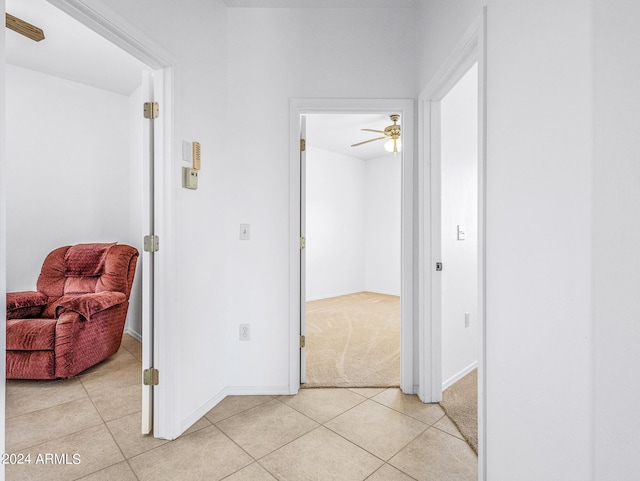 hall with light tile patterned floors, light colored carpet, and baseboards