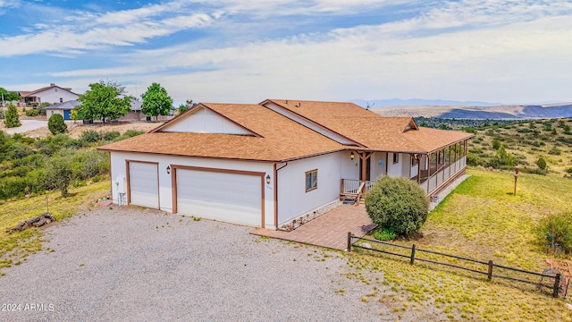 single story home with fence, roof with shingles, gravel driveway, an attached garage, and a mountain view