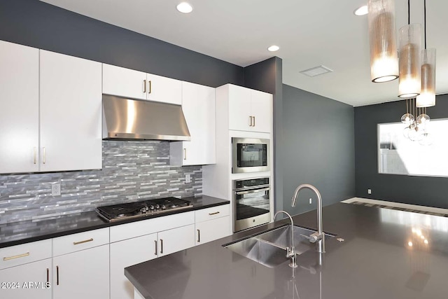 kitchen with decorative backsplash, stainless steel gas cooktop, sink, white cabinets, and hanging light fixtures