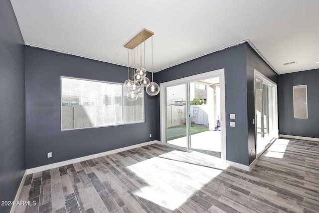 unfurnished dining area with hardwood / wood-style floors and a chandelier