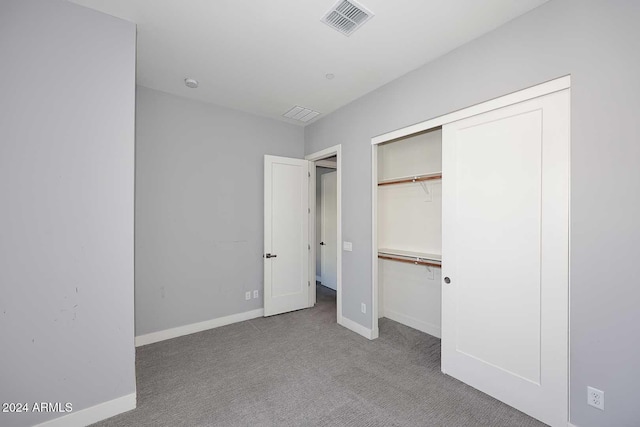 unfurnished bedroom featuring light carpet and a closet