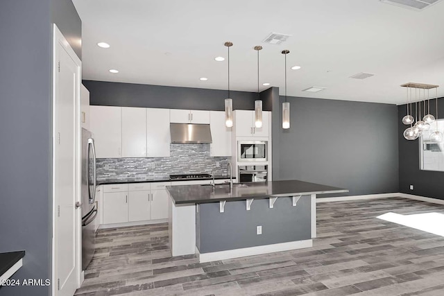 kitchen with a breakfast bar area, white cabinets, decorative light fixtures, and appliances with stainless steel finishes