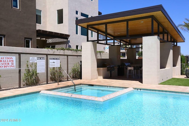 view of swimming pool featuring exterior bar, a hot tub, and an outdoor kitchen