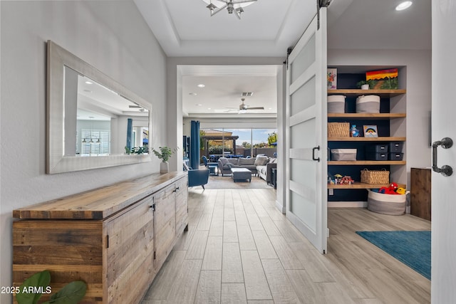 hallway featuring a barn door and light hardwood / wood-style flooring