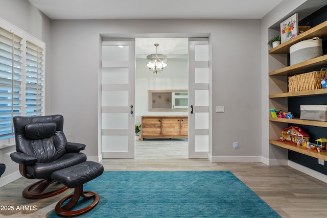 sitting room featuring an inviting chandelier and hardwood / wood-style floors