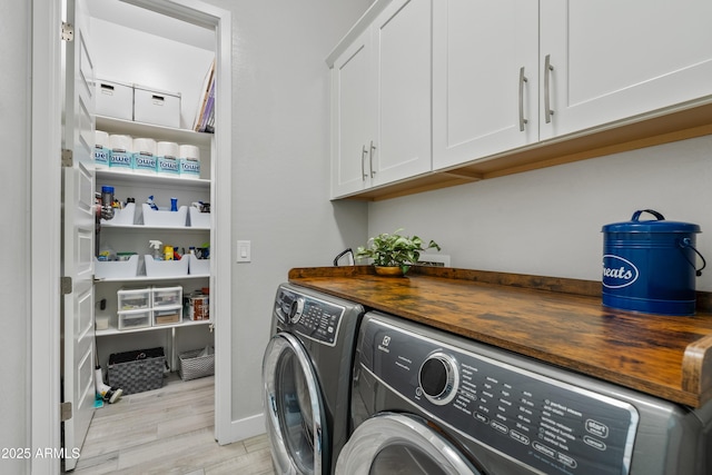 laundry area featuring cabinets, washing machine and dryer, and light wood-type flooring