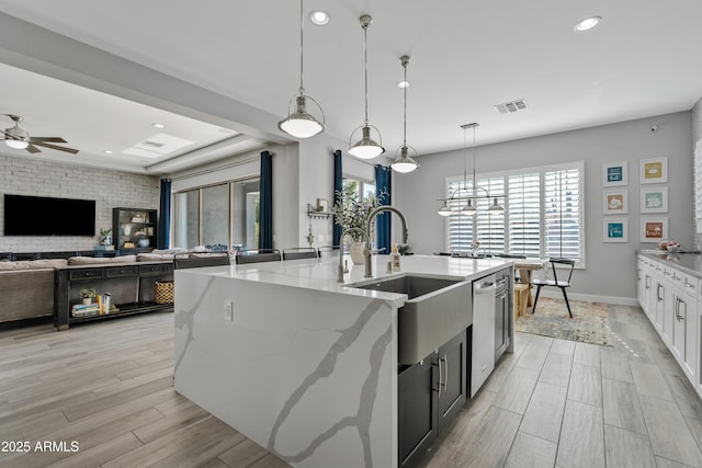 kitchen with a large island, white cabinetry, hanging light fixtures, light stone counters, and stainless steel dishwasher