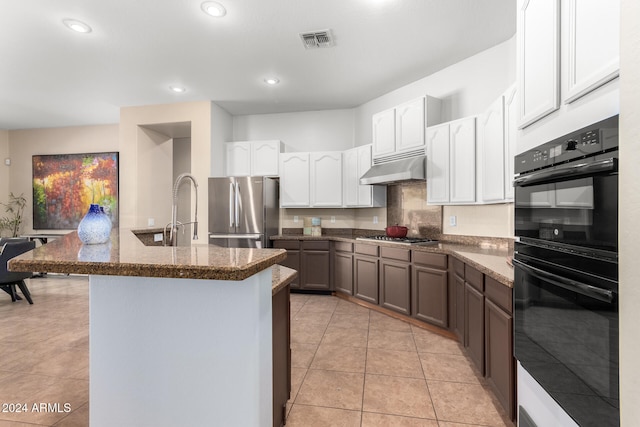 kitchen with white cabinetry, stainless steel appliances, and dark stone countertops