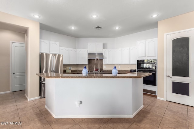 kitchen with white cabinetry, light tile patterned floors, double oven, and a kitchen island with sink