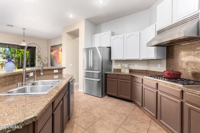 kitchen with stainless steel appliances, sink, light tile patterned floors, white cabinets, and tasteful backsplash