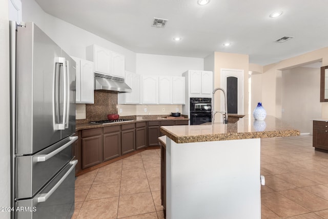 kitchen with decorative backsplash, an island with sink, appliances with stainless steel finishes, light tile patterned flooring, and sink