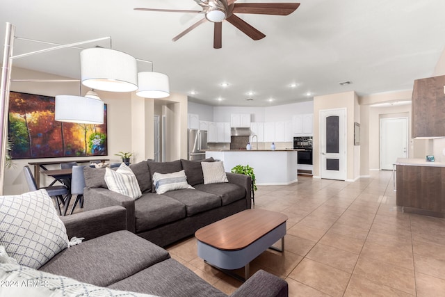 living room with sink, light tile patterned floors, and ceiling fan