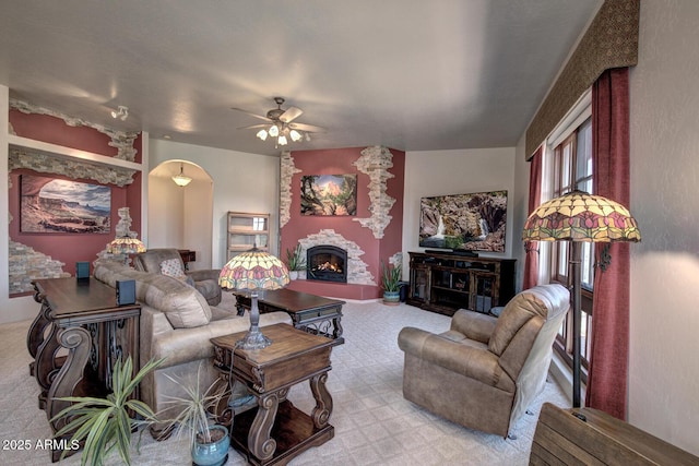 living area with light carpet, a fireplace, and ceiling fan