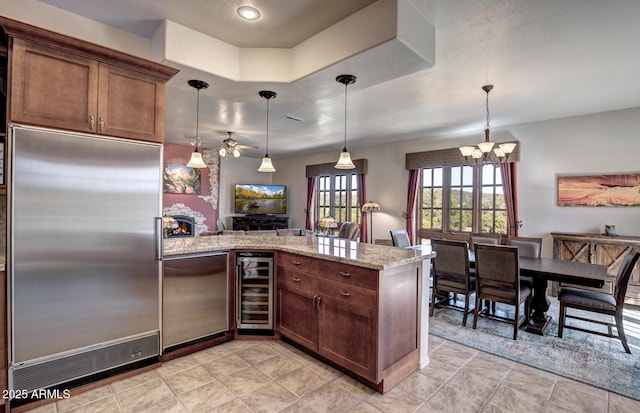 kitchen with light stone countertops, wine cooler, a peninsula, fridge, and built in fridge