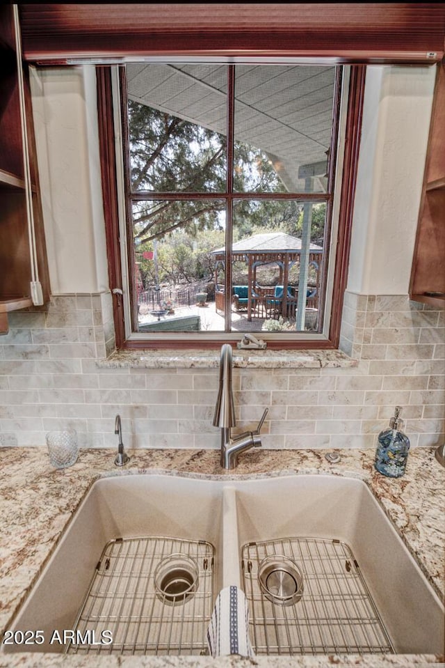 room details with light stone counters, decorative backsplash, and a sink