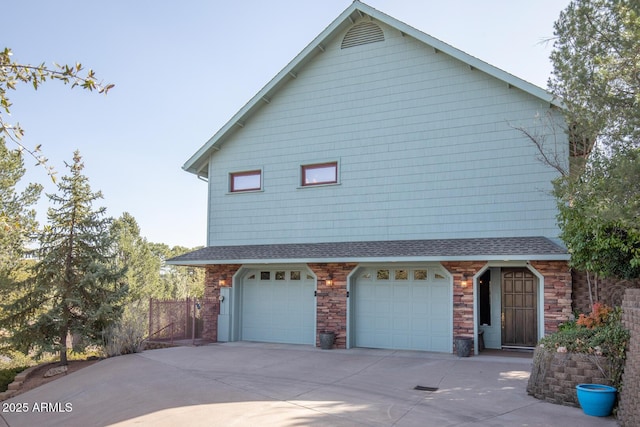 view of property exterior with a garage, stone siding, driveway, and fence