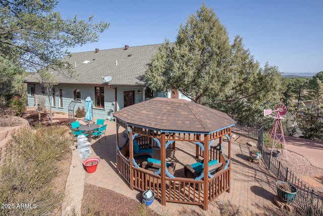 rear view of property with a gazebo and a shingled roof