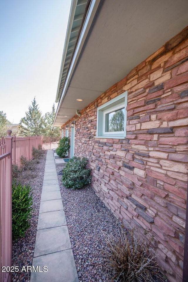 view of property exterior with stone siding and fence