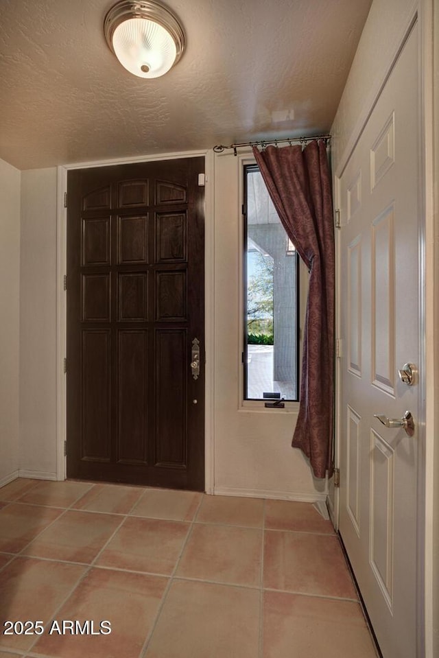 foyer entrance featuring light tile patterned floors and a textured ceiling