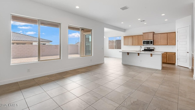 17841 W Windsor Blvd, Litchfield Park, AZ 85340 - kitchen with appliances with stainless steel finishes, light tile patterned flooring, light countertops, a sink, and an island with sink