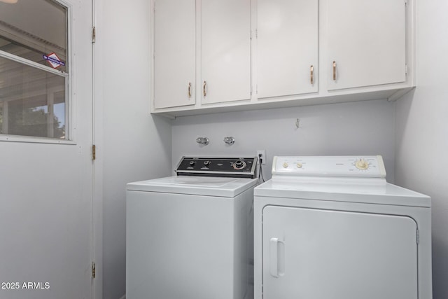 clothes washing area with cabinets and washer and dryer