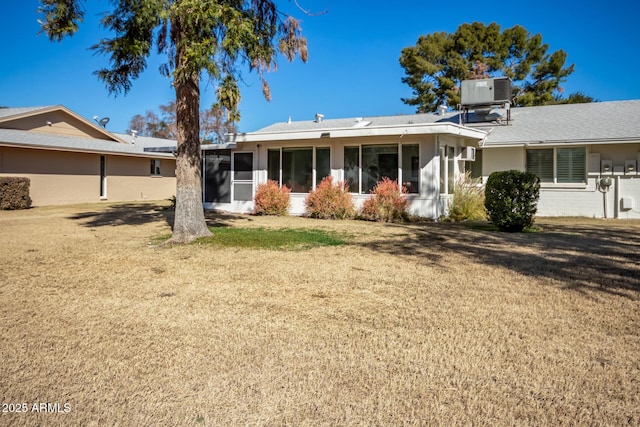 rear view of property with central AC unit, a yard, and a sunroom