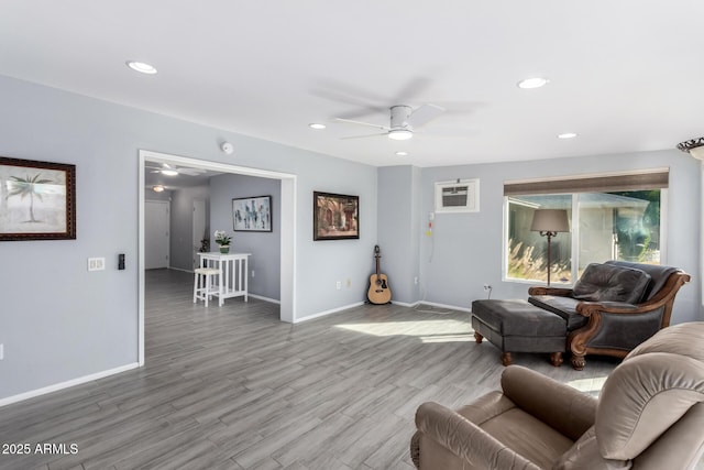 living room with hardwood / wood-style flooring, a wall mounted AC, and ceiling fan