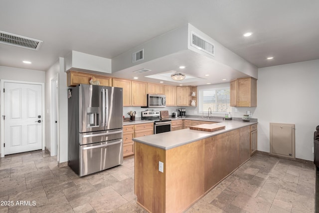 kitchen with sink, light brown cabinets, kitchen peninsula, and appliances with stainless steel finishes