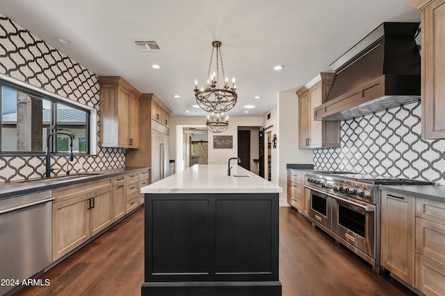 kitchen featuring decorative light fixtures, a sink, high quality appliances, wall chimney range hood, and a center island with sink