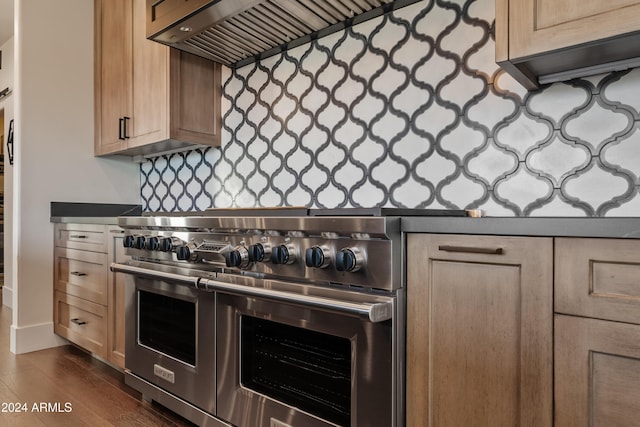 kitchen with wall chimney exhaust hood, double oven range, decorative backsplash, and light brown cabinetry