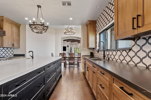 kitchen with visible vents, arched walkways, dark wood-style floors, decorative light fixtures, and a sink