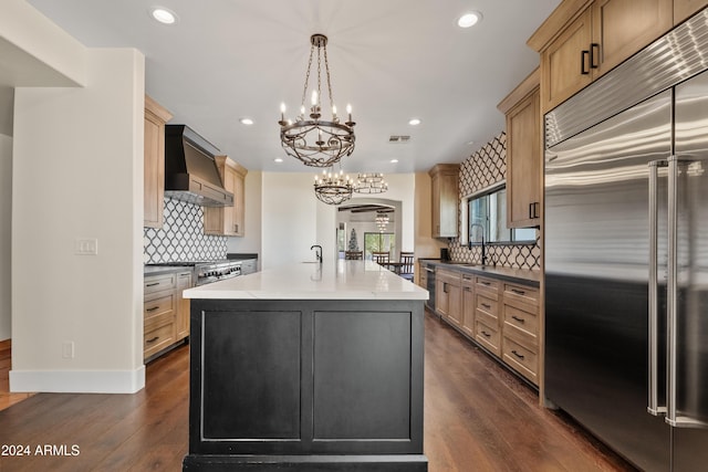 kitchen featuring a center island with sink, arched walkways, stainless steel built in fridge, custom exhaust hood, and pendant lighting