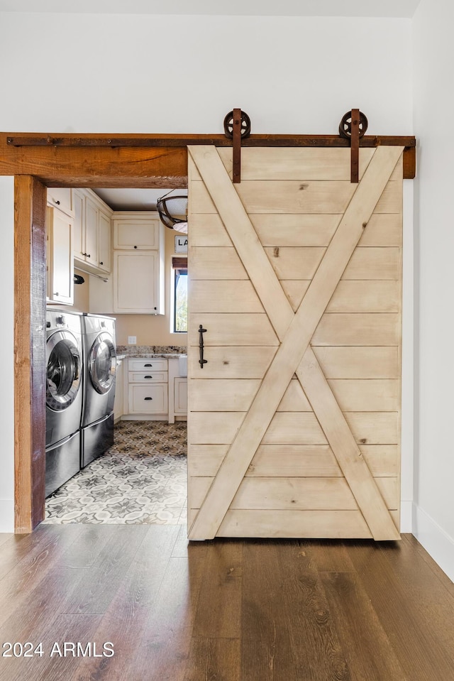 laundry room featuring cabinet space, a barn door, separate washer and dryer, and dark wood finished floors