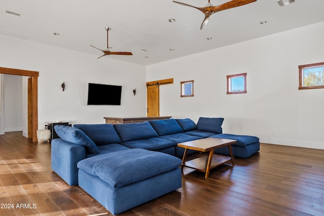 living area with dark wood finished floors, visible vents, ceiling fan, and a barn door