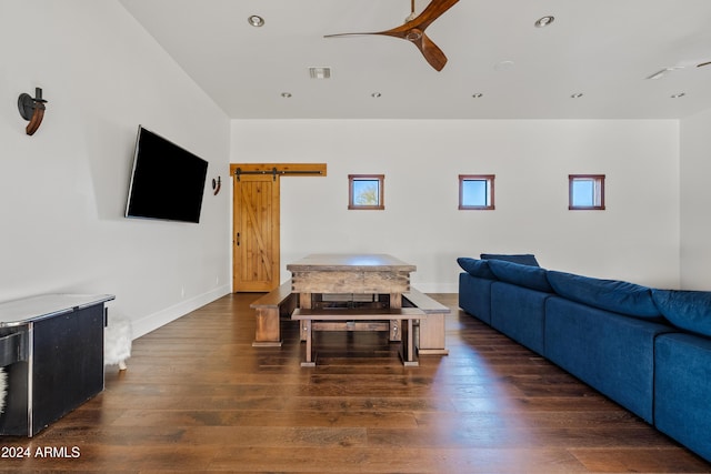 living area featuring dark wood finished floors, visible vents, ceiling fan, and a barn door