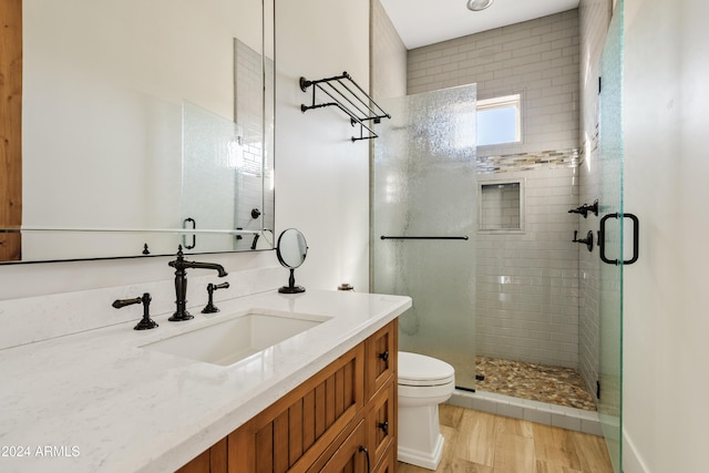 full bathroom featuring toilet, a stall shower, wood finished floors, and vanity