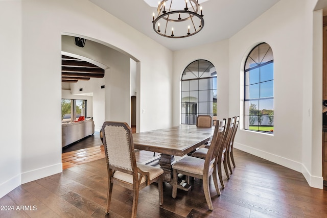 dining space featuring a chandelier, dark wood-style flooring, arched walkways, and baseboards