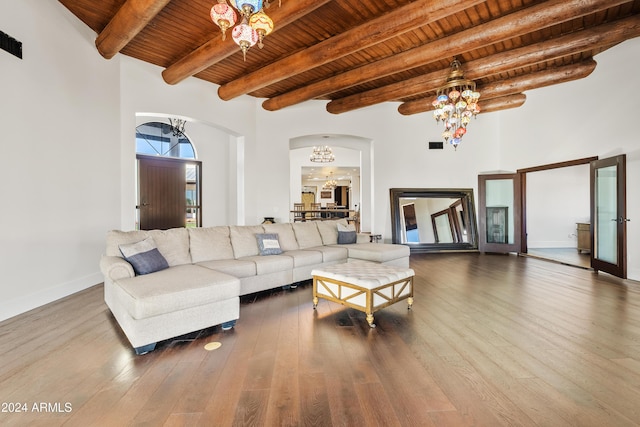 living room with a chandelier, arched walkways, wooden ceiling, wood finished floors, and beamed ceiling