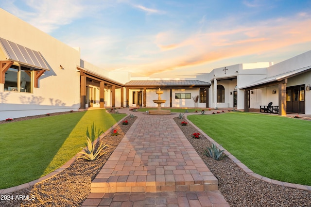 view of front facade with a front yard, metal roof, and stucco siding