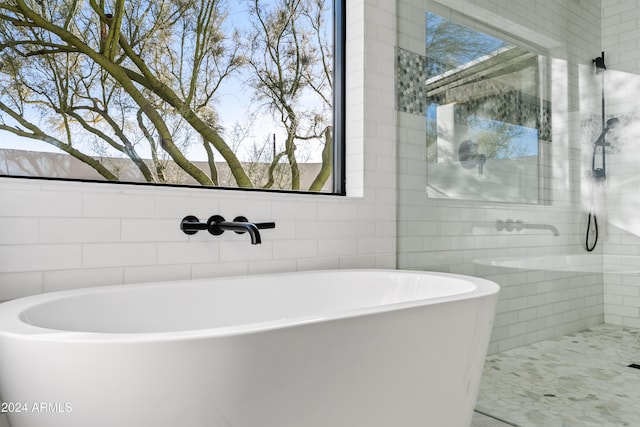 full bath with a freestanding bath and tile walls