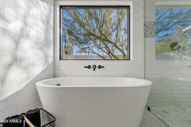 bathroom featuring a soaking tub and tile walls