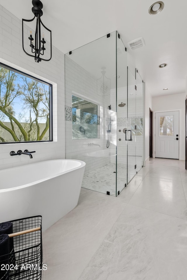 full bath featuring visible vents, a soaking tub, a shower stall, a chandelier, and tile walls