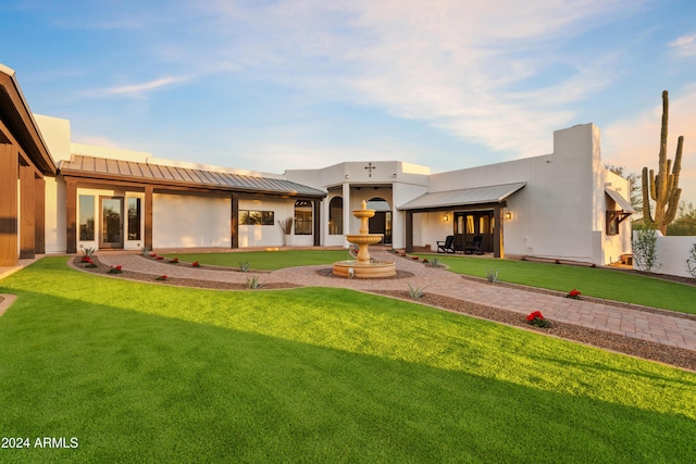 view of front of home with a standing seam roof, stucco siding, metal roof, and a front yard