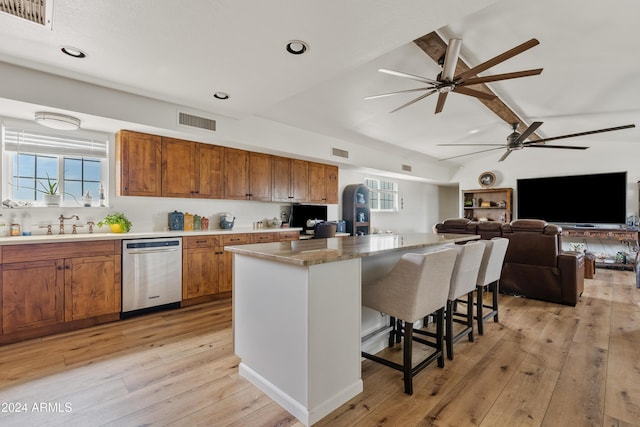 kitchen with dishwasher, a breakfast bar area, brown cabinetry, and visible vents